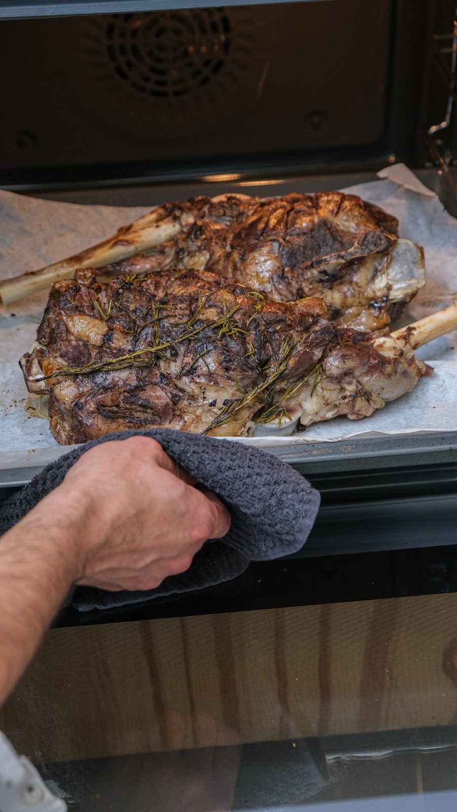 Fırın kuzu, two lamb shoulders with rosemary, coming out of the oven